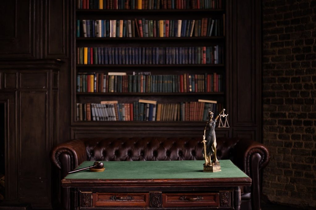 pexels photo 6077091 A classic study room with shelves of books, a gavel, and Lady Justice figurine on a green table.